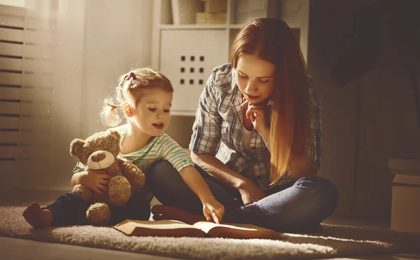 Gelukkige familie moeder en dochter lezen een boek in de avond — Stockfoto