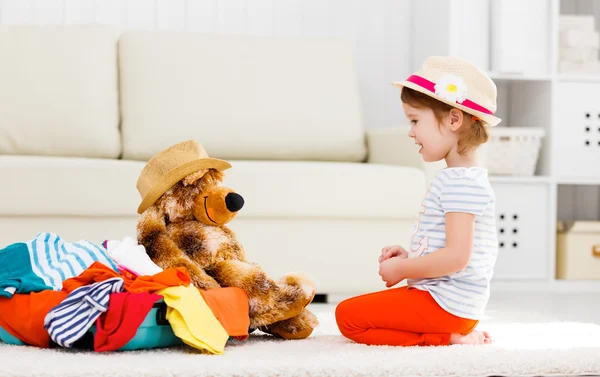 Lyckligt barn flicka samla resväska på semester — Stockfoto