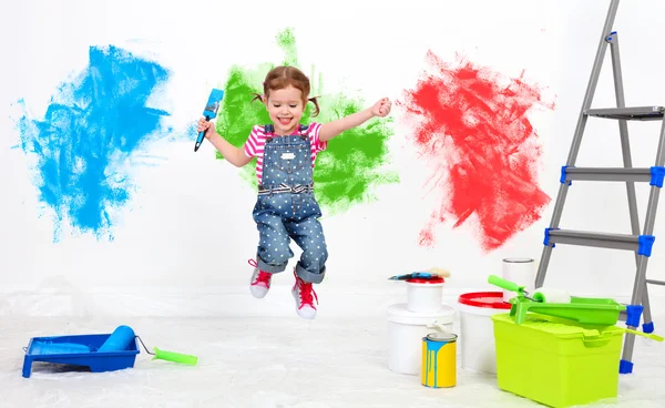 Happy funny child girl doing repairs, jumping and paint wall — Stock Photo, Image