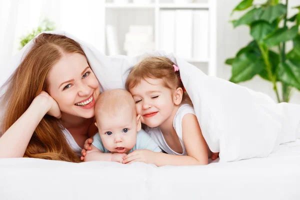 Glückliche Familienmutter und zwei Kinder, Sohn und Tochter im Bett — Stockfoto