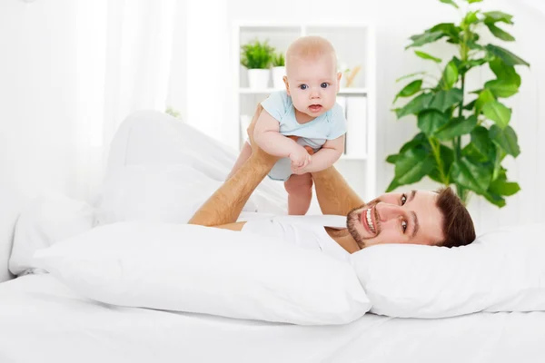 Feliz familia padre y bebé en la cama — Foto de Stock