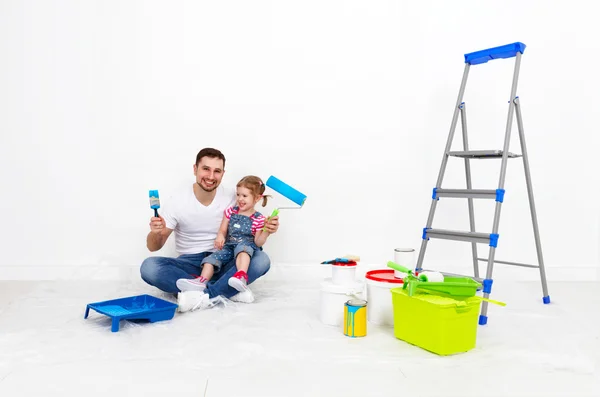 happy family father and child daughter making repairs, paint wal