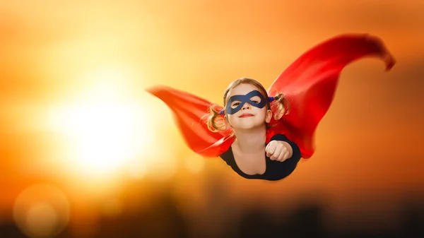 Criança menina super-herói voando através do céu ao pôr do sol — Fotografia de Stock