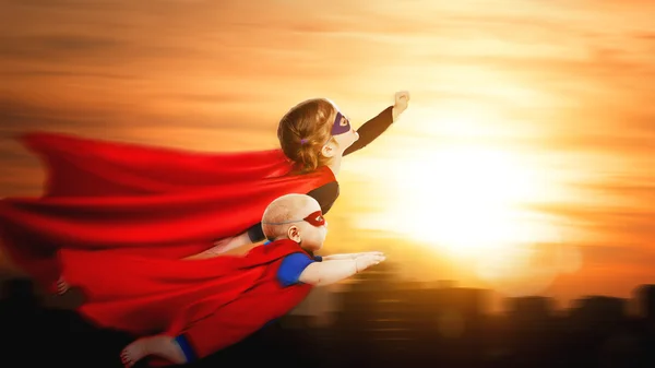 Children superheroes flying across sunset sky — Stock Photo, Image