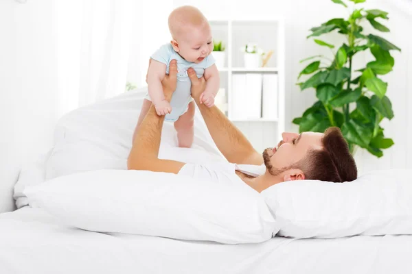 Gelukkig gezin vader en baby op bed — Stockfoto