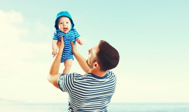 mutlu aile baba ve bebek oğlu deniz gün batımında sahilde