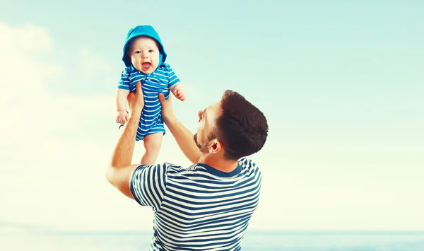 Szczęśliwa rodzina ojca i syna baby na plaży przez morze o zachodzie słońca — Zdjęcie stockowe