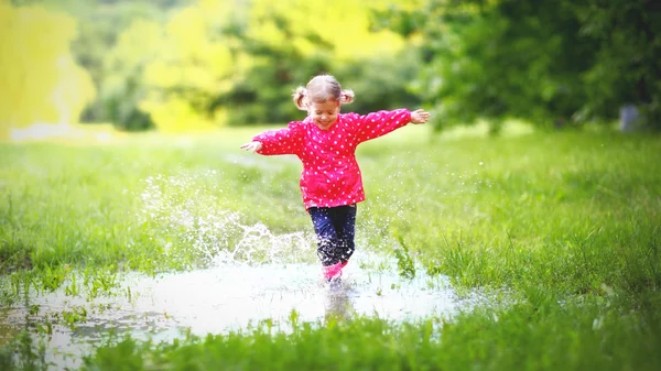 Bambina felice che corre e salta nelle pozzanghere dopo la pioggia — Foto Stock