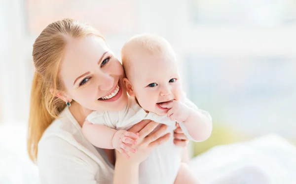 Gelukkige familie moeder met baby spelen en knuffelen in bed — Stockfoto