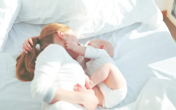 Gelukkige familie moeder met baby spelen en knuffelen in bed — Stockfoto