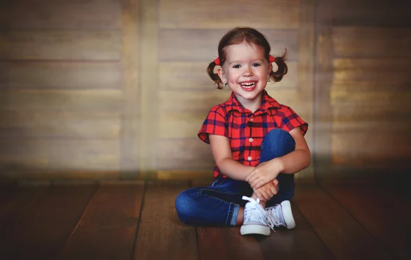 Happy child girl laughing at empty wooden wall — Stock Photo, Image