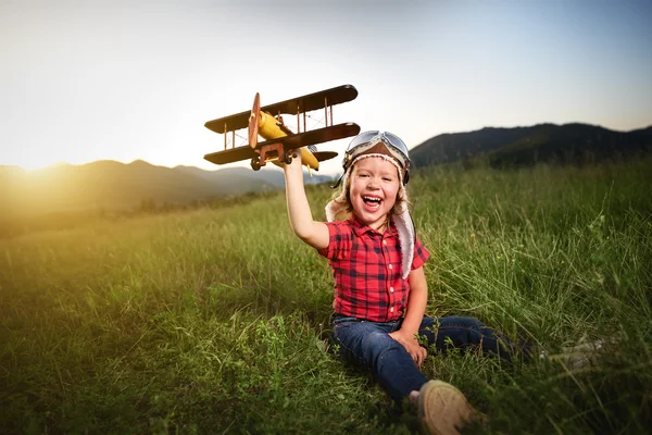 Criança feliz sonhos de viajar e brincar com um pil de avião — Fotografia de Stock