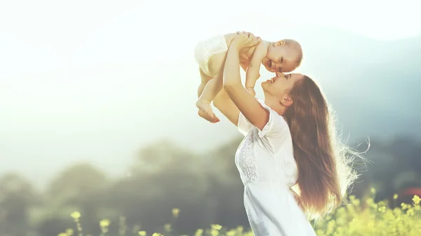 Buitenshuis en gelukkige familie. moeder gooit baby omhoog, lachen en playi — Stockfoto