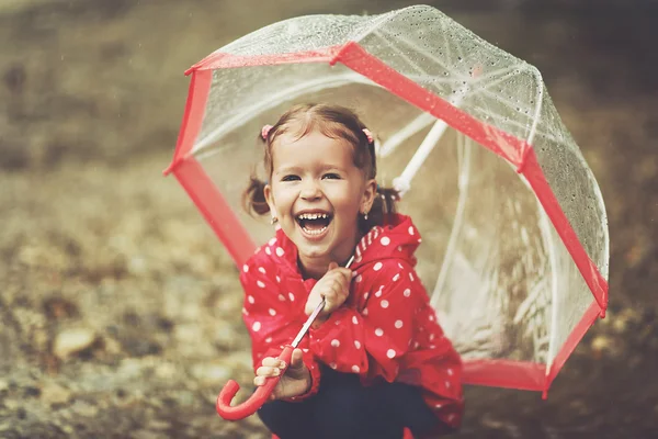 Lyckligt barn flicka skratta med ett paraply i regn — Stockfoto