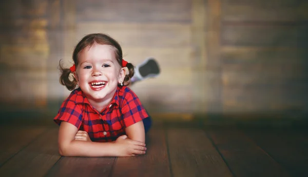 Fröhliches Kindermädchen lacht über leere Holzwand — Stockfoto