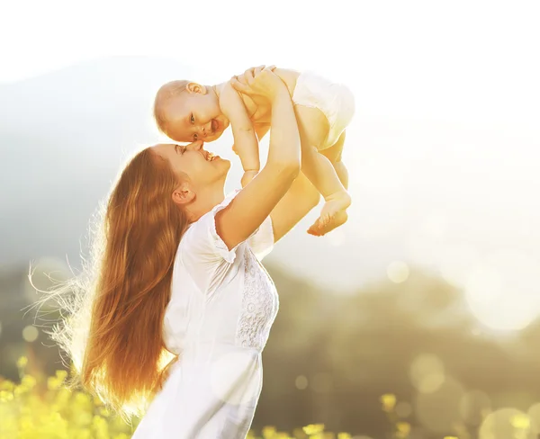 Buitenshuis en gelukkige familie. moeder gooit baby omhoog, lachen en playi — Stockfoto