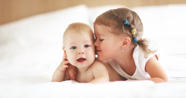 Счастливая семья сестра целует младшего брата — стоковое фото