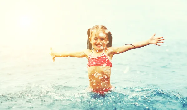 Fille heureuse enfant joue et nage avec éclaboussures sur la plage — Photo