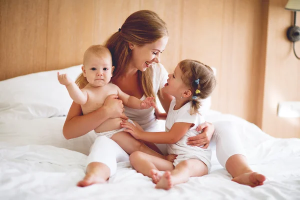 快乐家庭的母亲和两个孩子，儿子和女儿在床上 — 图库照片