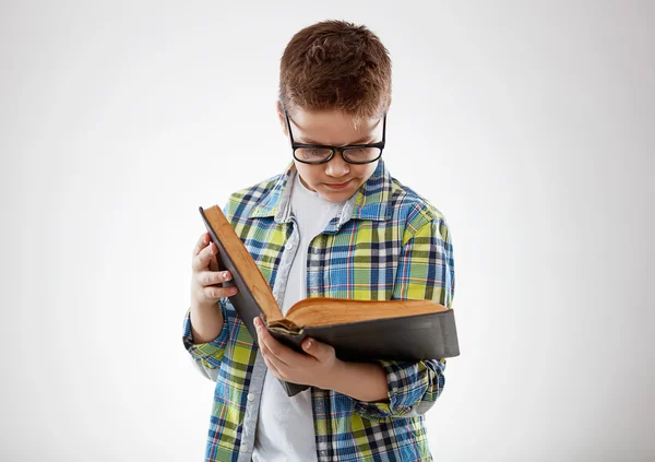 儿童小男孩少年戴着眼镜雷丁在灰色的背景上的书 — 图库照片