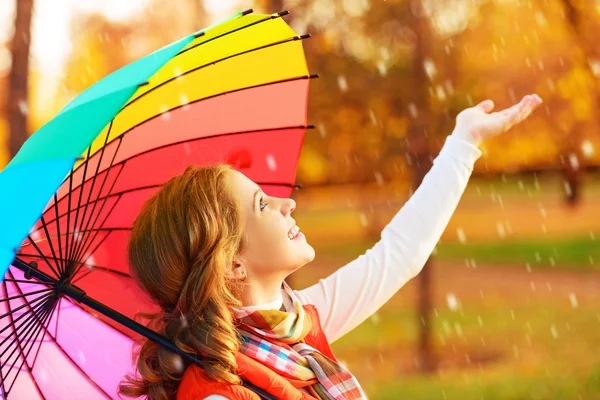 Mulher feliz com arco-íris guarda-chuva multicolorido sob a chuva em par — Fotografia de Stock