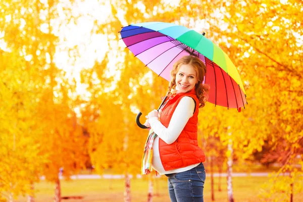 Mujer embarazada feliz con paraguas colorido en el paseo de otoño — Foto de Stock