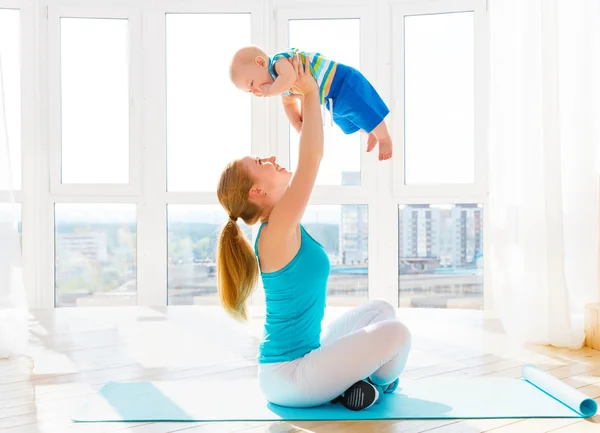 Спортивная мама занимается фитнесом и йогой с ребенком дома — стоковое фото