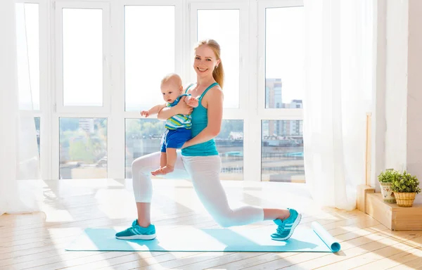 Esportes mãe está envolvida em fitness e ioga com o bebê em casa — Fotografia de Stock