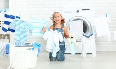 Çocuk eğlenceli giysi ve gülüyor laund içinde yıkamak için mutlu küçük kız