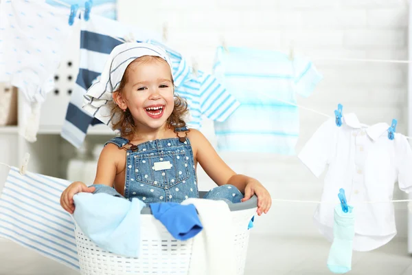 Niño divertido feliz niña para lavar la ropa y se ríe en laund —  Fotos de Stock