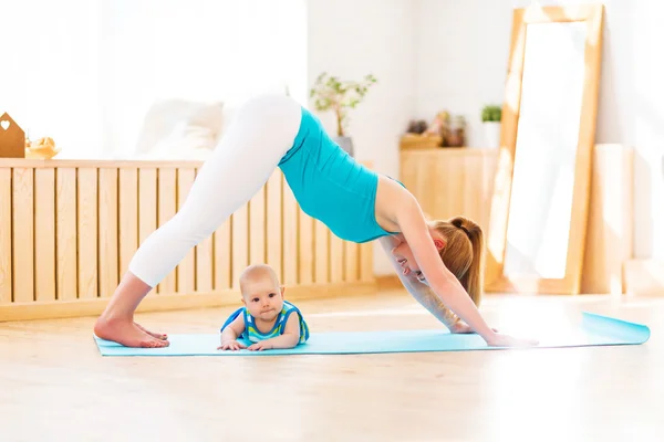 Sportowe matka jest zaangażowany w fitness i jogi z dzieckiem w domu — Zdjęcie stockowe