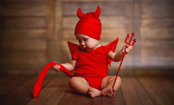 Смешной ребенок в костюме дьявола на деревянном фоне — стоковое фото