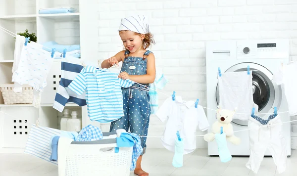 Niño divertido feliz niña para lavar la ropa y se ríe en laund —  Fotos de Stock