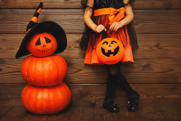 Gambe di bambina in costume da strega per Halloween con zucca — Foto Stock