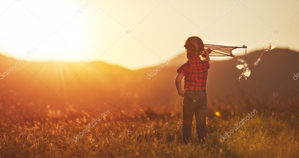 happy child girl with a kite on meadow in summer