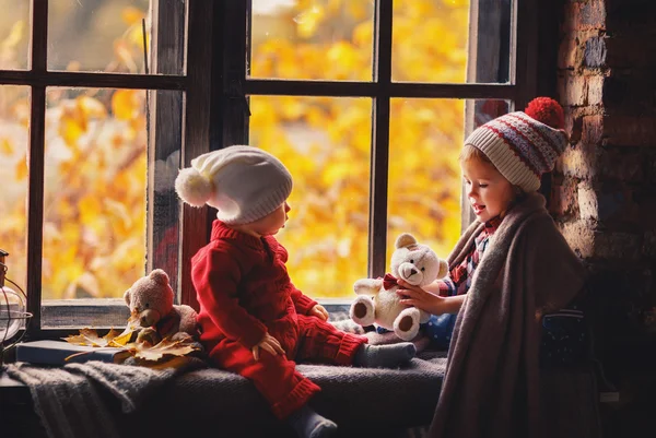 Feliz niños hermano y hermana jugando cerca de la ventana caída —  Fotos de Stock