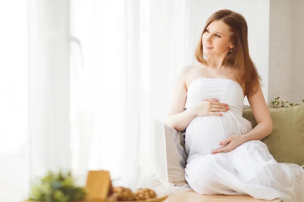 Mild elegant gravid kvinna i en vit klänning — Stockfoto