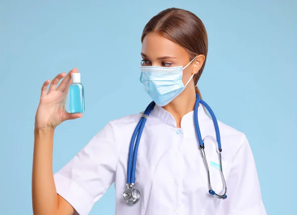 Mulher Uniforme Médico Máscara Demonstrando Frasco Desinfetante Durante Pandemia Coronavírus — Fotografia de Stock