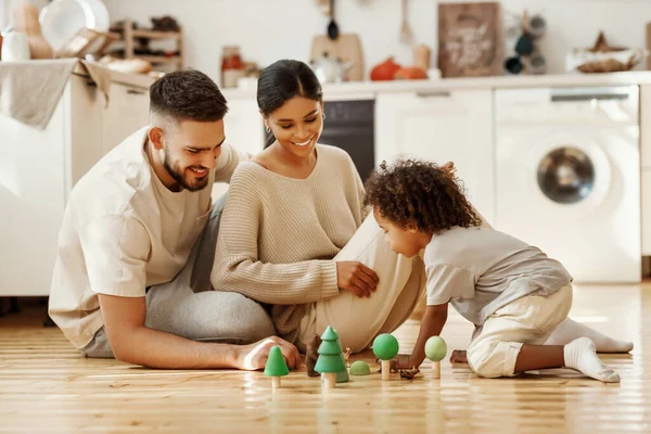 幸せな多民族の両親と男の子遊びますおもちゃで床の上に居心地の良いキッチン ホーム — ストック写真