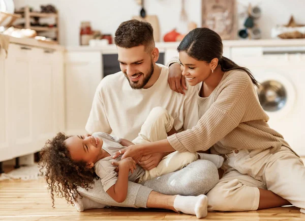 Mutlu aile çok ırklı anne, baba ve oğul gülüyor, oynuyor ve evdeki rahat mutfakta gıdıklanıyor.