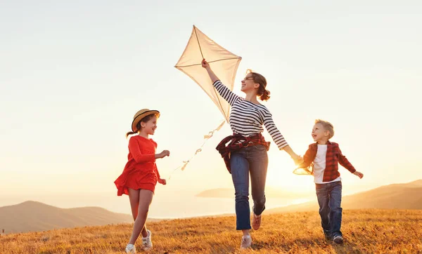 幸せな家族の母親と子供たちは太陽の下で自然の上で凧を打ち上げ — ストック写真