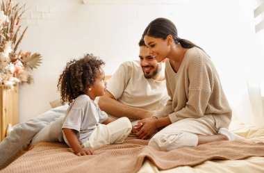 Mutlu aile çok ırklı anne, baba ve oğul gülüyor, oynuyor ve yatak odasında gıdıklanıyor.