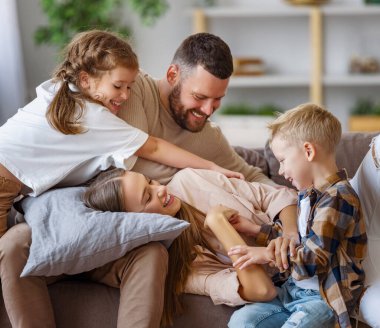 Mutlu aile anne baba ve çocuklar evde kanepede eğleniyorlar.