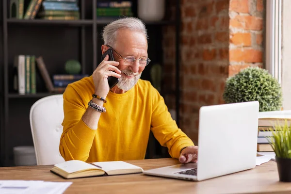 Stylowy Starzec Uśmiecha Się Odbiera Telefon Siedząc Przy Biurku Przytulnym — Zdjęcie stockowe