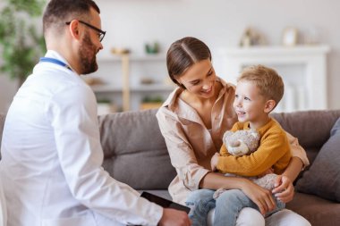Dost canlısı bir çocuk doktoru aile doktorunun resepsiyonunda annesiyle birlikte mutlu bir çocuk hasta.