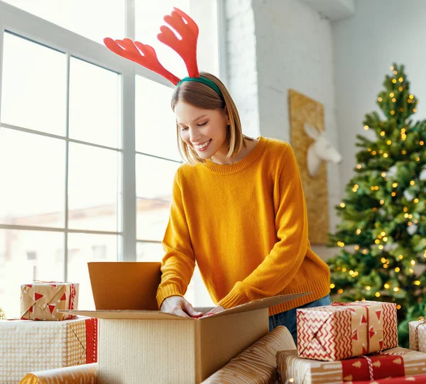 Happy Young Woman Christmas Headband Smiling Looking Camera While Wrapping — Stock Photo, Image