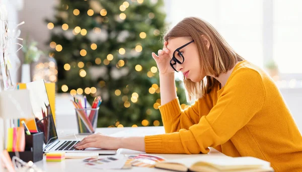 クリスマス リモート プロジェクトで作業しながら 頭に触れてノートパソコンでデータを閲覧するメガネの疲れ若い女性の側面図 — ストック写真