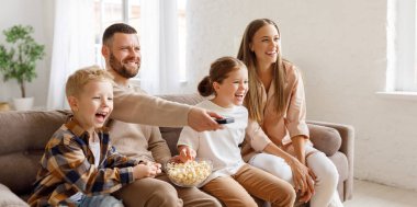 Mutlu aile babaları ve çocuklar patlamış mısır yer ve kanepede oturup komik bir film izlerken gülerlerdi.