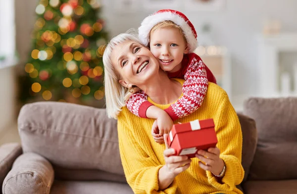 Schattig Kind Knuffelen Blij Oudere Vrouw Zitten Bank Met Kerstcadeau — Stockfoto