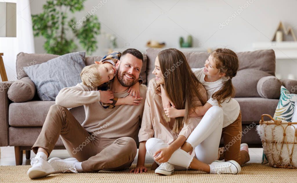 Happy family mother father and children at home on floor next to the sof